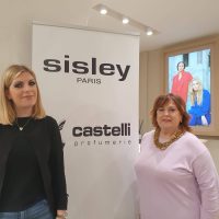 Profumerie Castelli con Sisley ed Elena Mirò clienti in posa davanti al cartello